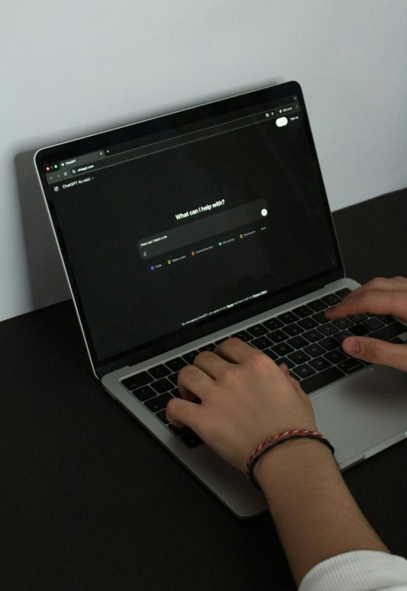 Une personne utilise un ordinateur portable affichant une interface de chatbot pour explorer des solutions IA professionnelles dans un espace de travail moderne.