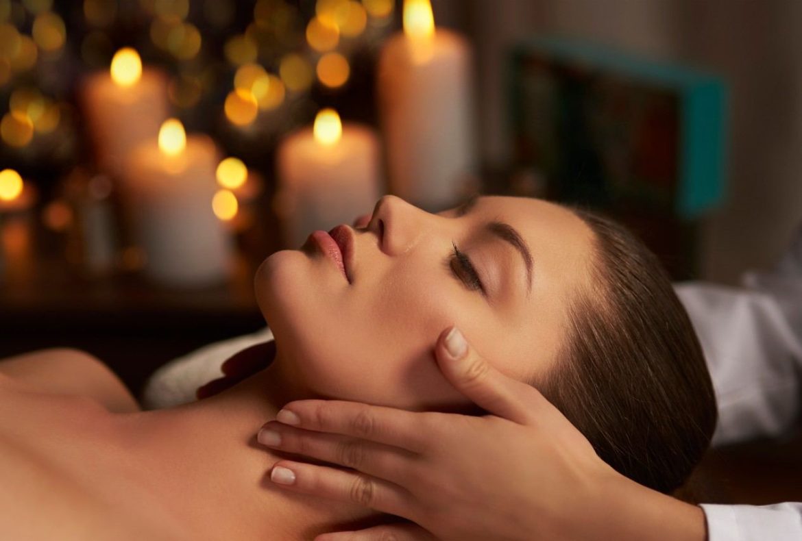 Une femme recevant un massage facial Kobido pour sa routine beauté dans une ambiance relaxante aux bougies.