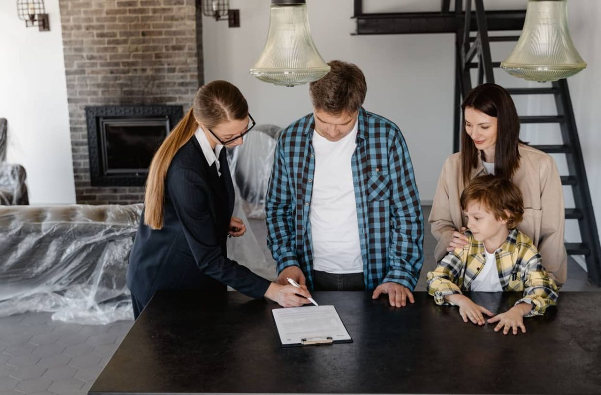 Une famille avec un enfant signe un contrat de logement avec une agente immobilière, une étape essentielle pour demander la prime de déménagement CAF.