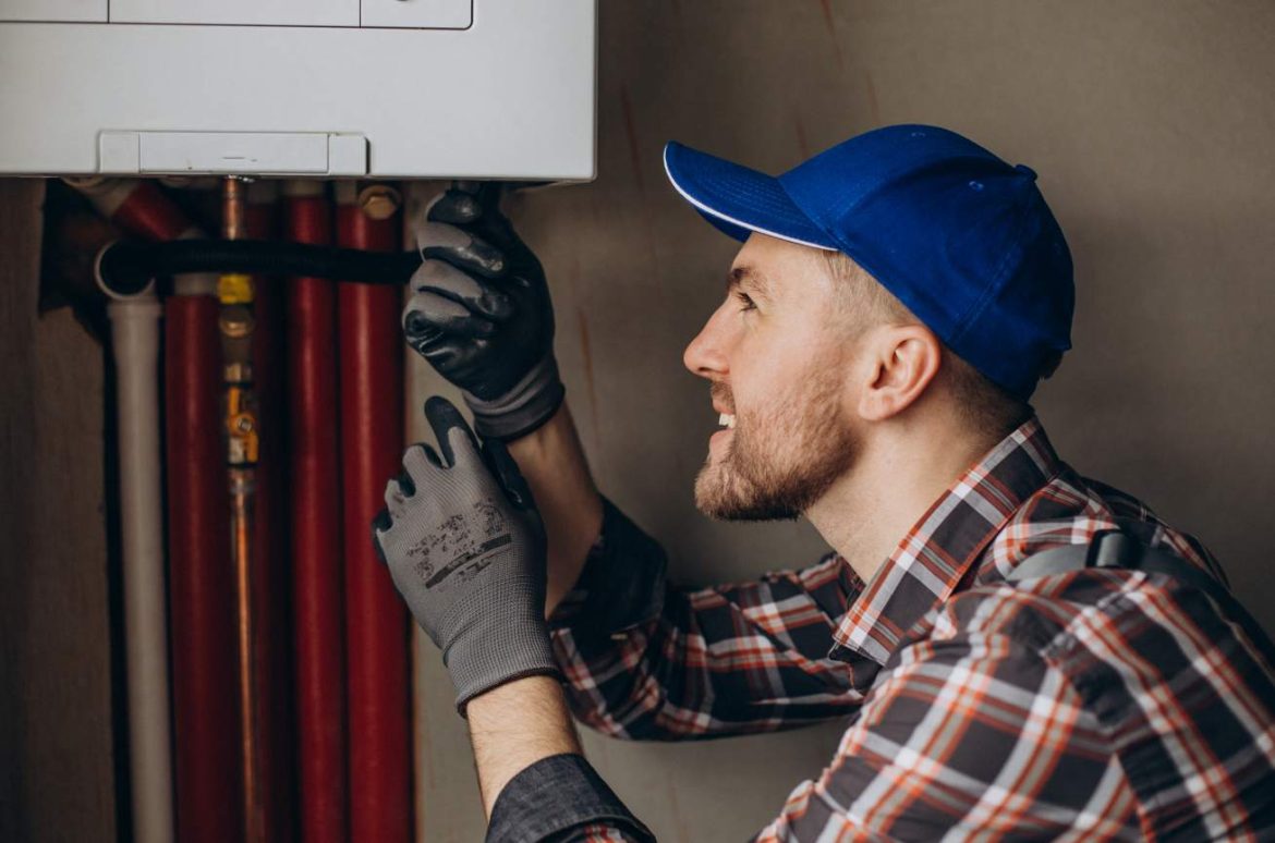 Un technicien en chemise à carreaux et casquette bleue effectue la maintenance d'une chaudière pour prolonger durée de vie système chauffage.
